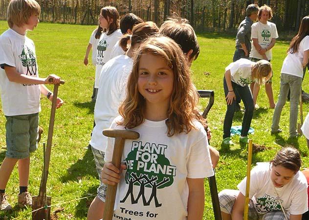 Gruppe von Kindern bei der Plant for the Planet Akademie, ein Mädchen mit einer Schaufel steht lächelnd im Vordergrund