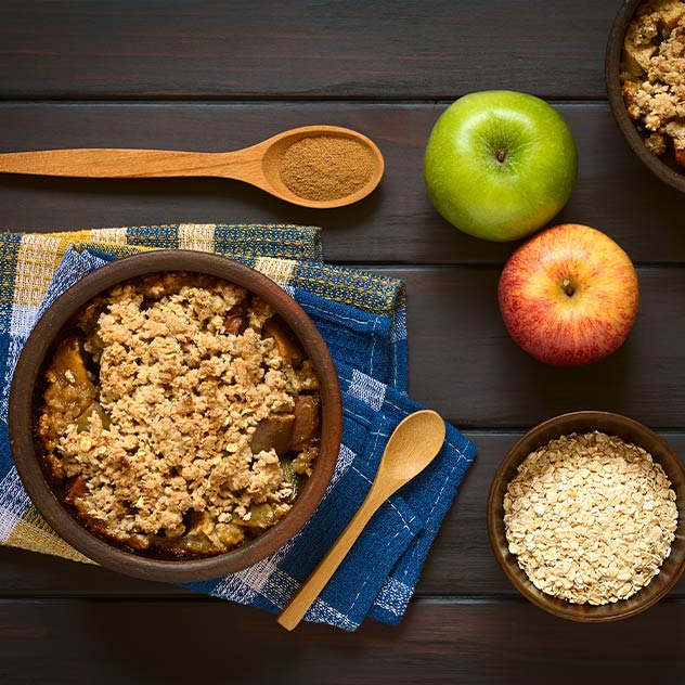 Apple Crumble mit zwei frischen Äpfeln und Haferflocken in einer Schüsse- – Adobestock-Ildi